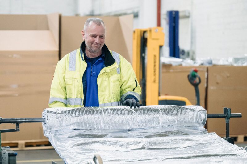 Mitarbeiter rollt ISUM Dämmfolie für die Weiterverarbeitung auf